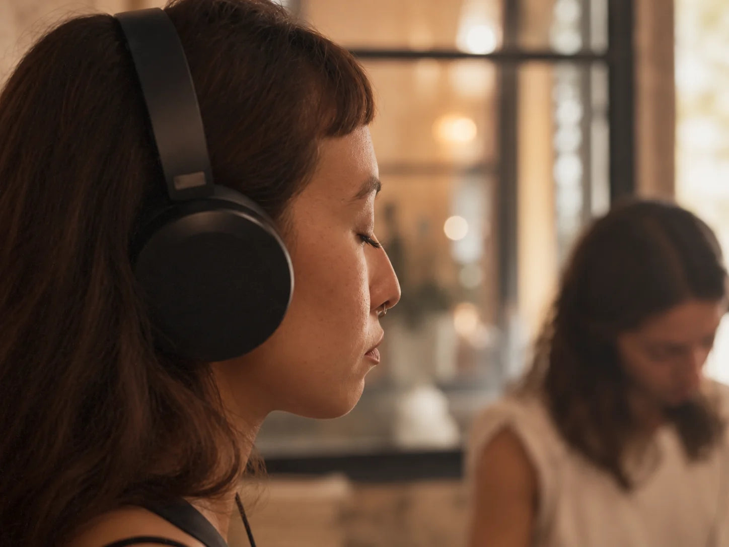 A guest listens with eyes closed at an INARA sensory lounge.